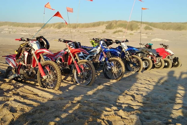Row of dirt bikes and ATVs on sand dunes